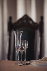 Set of empty glasses and dishware on table indoors. Transparent glasses on glossy shelf in luxury restaurant. Empty champagne glasses before the ceremony