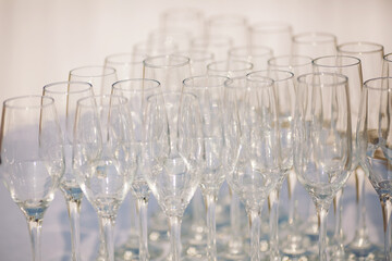 Set of empty glasses and dishware on table indoors. Transparent glasses on glossy shelf in luxury restaurant. Empty champagne glasses before the ceremony