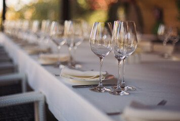 elegant dinner table setting in restaurant or hotel with wine glasses. tableware Glasses, flower fork, knife served for dinner in restaurant