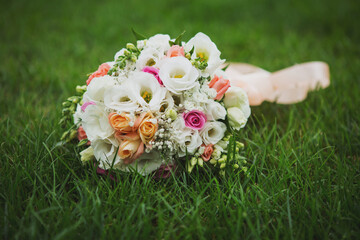 Obraz na płótnie Canvas close up photo of a bridal bouquet on the grass