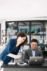 Two Asian businesswoman and man discuss investment projec with tablet laptop computer.