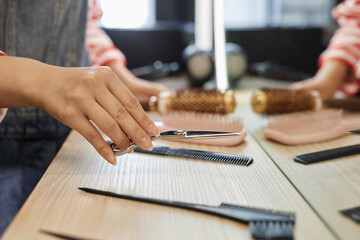 Closeup of female hairstylist holding professional scissors while preparing to work in beauty salon, copy space