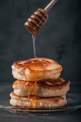 Pancakes are drizzled with honey. Dark background. - 675249153