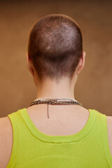 Back view of unrecognizable young woman with buzzcut facing away from camera in studio