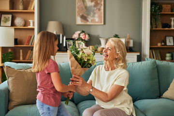 Happy grandma thanking granddaughter for flower bouquet