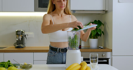 Woman cuts spinach on board. Preparing healthy smoothie concept