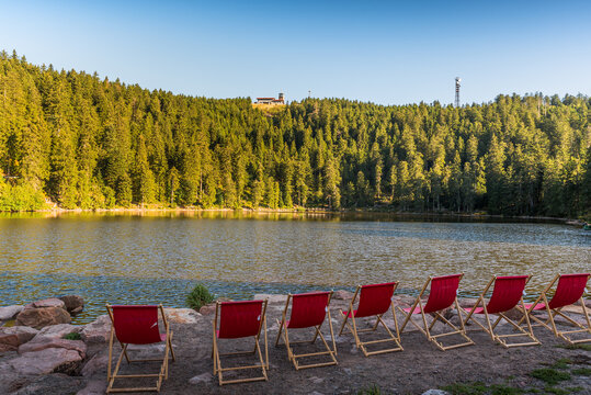 Red, empty deckchairs at Mummelsee Lake with view of the Hornisgrinde, Black Forest National Park, Seebach, Baden-Wuerttemberg, Germany