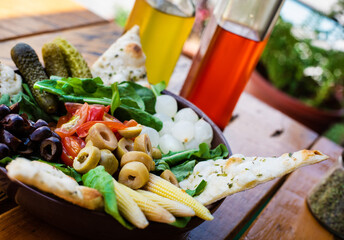 Closeup of a healthy green salad with olives, little onions, tomato and pickles. Mediterranean food.