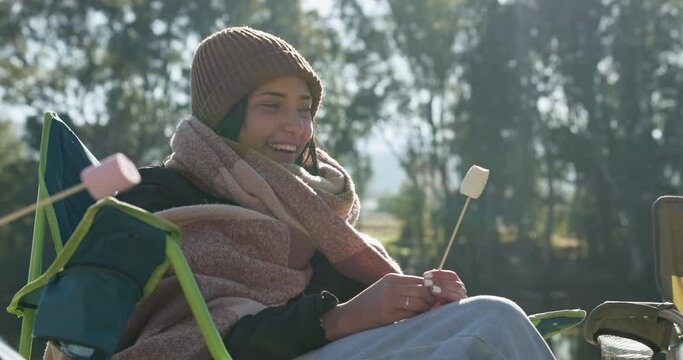 Marshmallow, camping or friends by campfire to relax on holiday, vacation or weekend break on outdoors. Travel, campers or happy woman talking, speaking or enjoying conversation on fun trip together