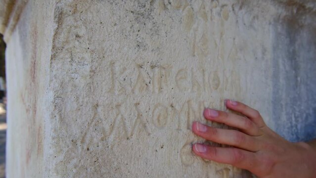 female hand traces inscriptions on stone ruins, mediterrenean old city phaselis Turkey. Phaselis or Faselis was Greek and Roman city on coast of ancient Lycia. Its ruins are located town Tekirova