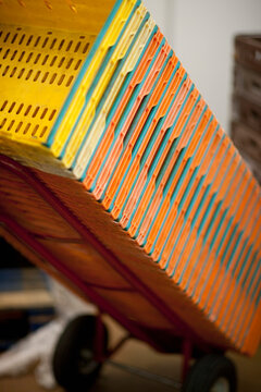Close up of a stack of plastic crates leaning on a lifting cart
