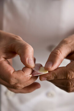 Close up of a chef hands peeling a garlic clove
