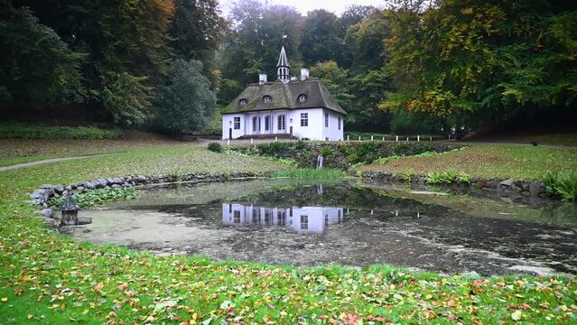 Footage of Lieselund Castle (Liselund Slot),set against a backdrop of a charming small pond and cascading waterfall. Lieselund Castle picturesque escape  touch of natural beauty and historical charm.