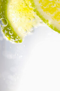 Extreme close up of slices of lime floating in sparkling water
