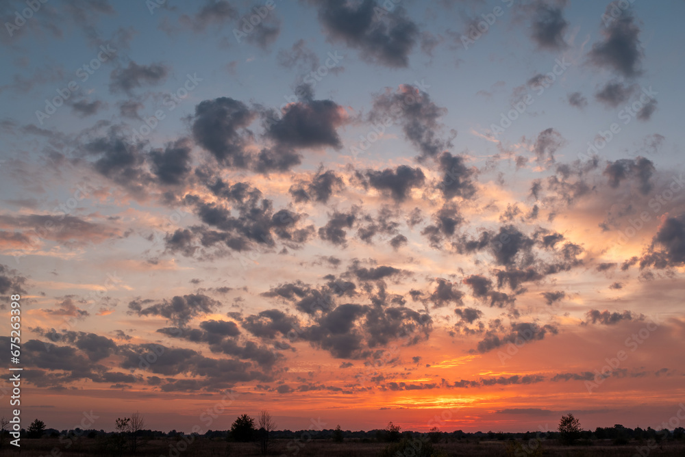 Wall mural Bright dramatic sunset in the countryside. Vivid clouds in sky after sun went over horizon