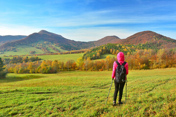 Woman backpacker on hiking trail in the mountains in autumn sunny day, Low Beskids (Beskid Niski) - obrazy, fototapety, plakaty
