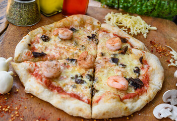 Traditional homemade Italian pizza with tomato, cheese, shrimps and black olives. Mozzarella. Olive oil. Food photography. Pizza cut into slices.