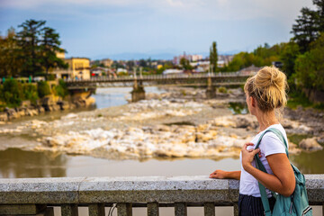 A traveler with a backpack stands with her back to the camera against the backdrop of the Kutaisi cityscape. Selective focus. Georgia, Caucasus