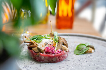 Beef tartare, tartar steak with capers, onion, pickles, on a plate, selective focus. Dish of raw ground beef meat.