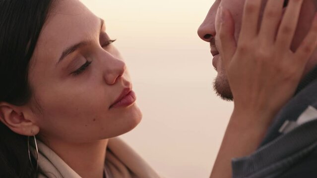 Closeup of a young woman caressing her boyfriend's face, sharing a tender kiss, expressing deep affection and love