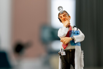 Close-up shot of a ceramic figurine of a doctor in a white coat with frontal reflector on his...