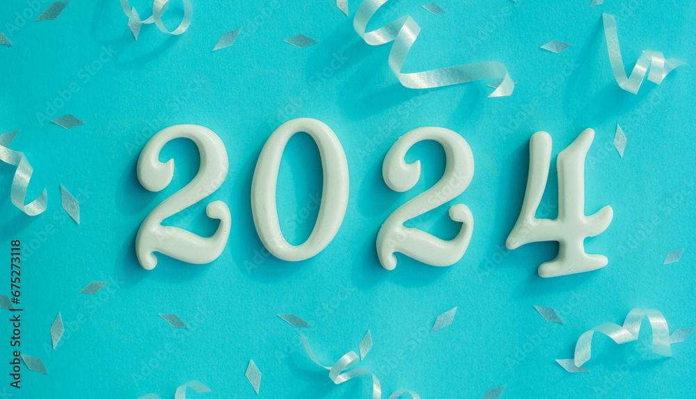 Wall mural close up number 2024 shape wood on blue color background with rolling ribbon and confetti for happy 