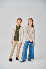 Fototapeta premium happy preteen friends in casual winter clothes on gray backdrop, smiling at camera, fashion concept