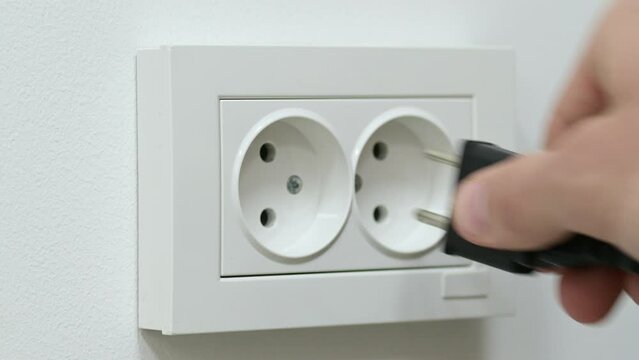 Man turning off appliances from wall socket. Unplugging electronic devices from the socket