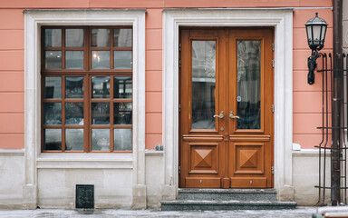 Old brown wooden window with rectangular frames for glass, a door and a house pink facade. Lviv, Ukraine.