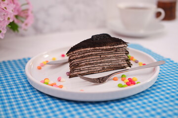 Piece of homemade chocolate crepes cake on a white plate