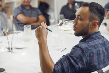 Close up portrait of young professional man tasting white wine.