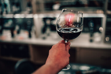 man hand holding a glass with red wine in a restaurant