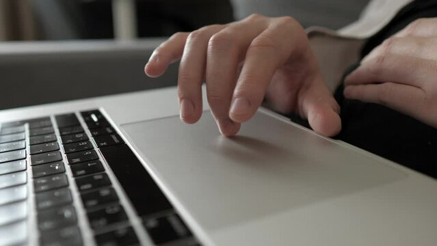 Male developer hands scroll and swipe on laptop touchpad looking on display in office. Closeup a pair of male hands using laptop touch pad at home. The fingers are clicking on touchpad.