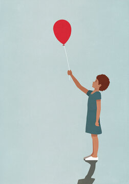 Girl holding red balloon on blue background
