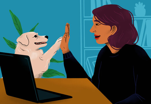 Happy woman high fiving with dog at laptop
