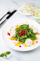 arugula salad with peach slices and red berries on a white plate top view