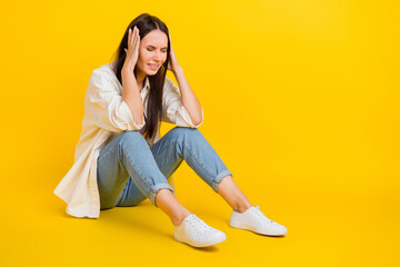 Full length profile photo of stressed unsatisfied person sit floor hands touch head empty space isolated on yellow color background