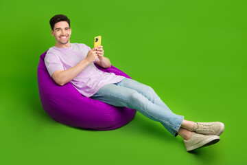 Full length photo of nice stylish man sitting soft chair using modern device apple iphone empty...