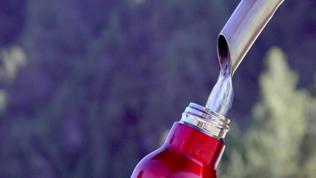 An empty thermos flask is filled with water at a fountain tap.
