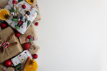 Wrapped gifts and Christmas tree decorations with candies laid out on a white background copy space