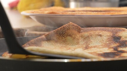 Spatula lifting a pancake, revealing underside texture. The action depicts the turning process...