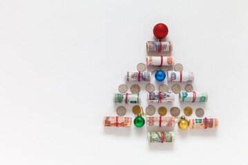 Unusual Christmas tree made of twisted Russian ruble banknotes and coins on white background....