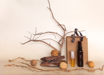 Advertisement for nourishing natural anti-aging cosmetics with walnut oil. Bottles with cosmetic products and walnuts on podium made of stone against background of dry tree branches on pastel backdrop