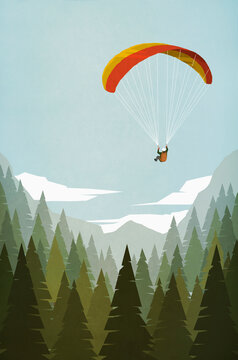 Man paragliding over mountain forest treetops
