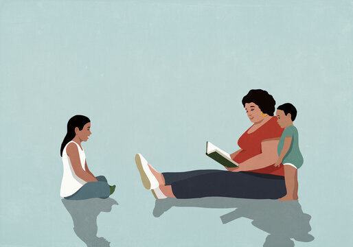 Hispanic mother sitting and reading book to daughter and baby son
