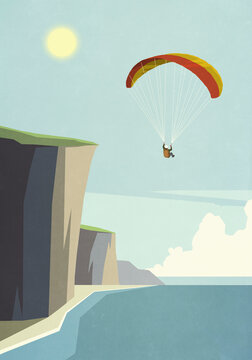 Man paragliding over sunny ocean cliffs

