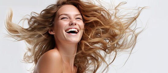 The young woman with her hair flowing in the wind was shocked as she stood against a white isolated background for her portrait Her beauty and happy face captured the essence of a free spiri - obrazy, fototapety, plakaty