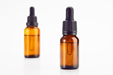 Two brown vials with black dropper caps isolated on white.