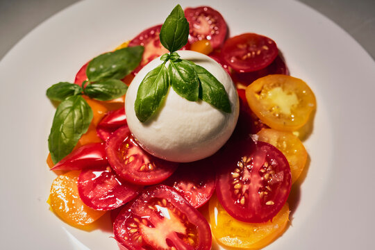 Close up still life fresh caprese salad with juicy tomatoes, whipped mozzarella and fresh basil
