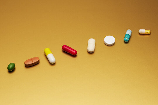 Still life arrangement variety of medication pills and capsules on yellow background
